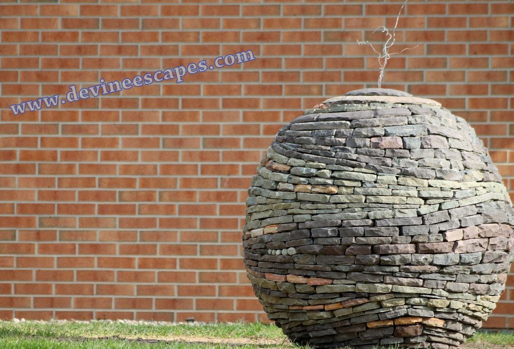 dry stone sphere garden sculpture with brick wall