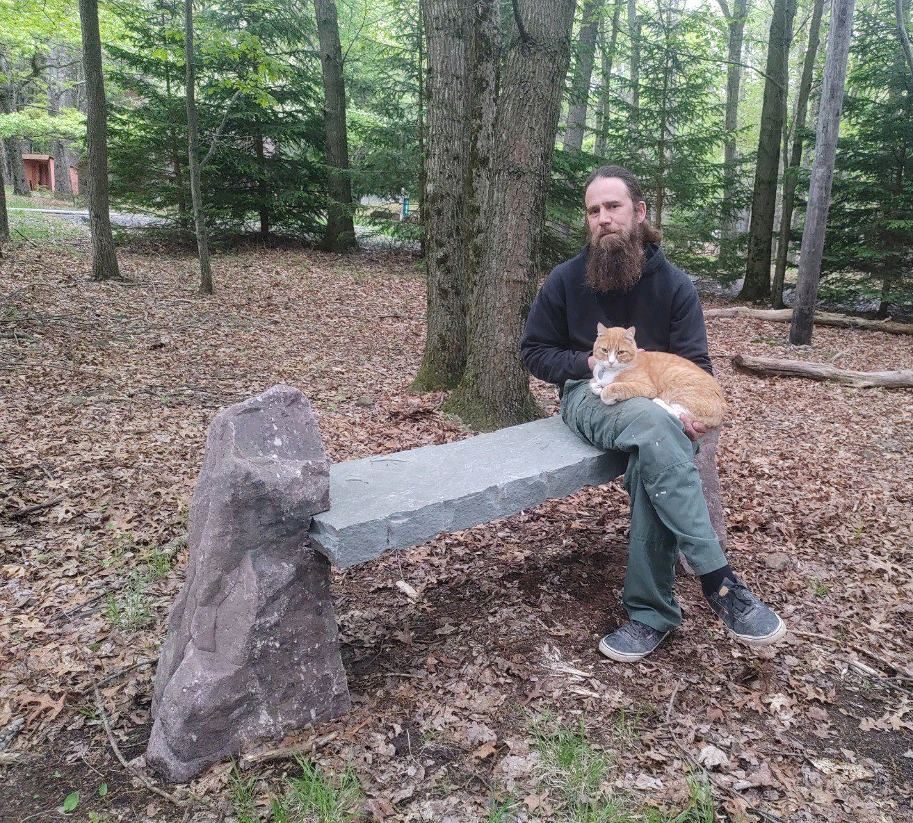 handsome man holding cat on stone bench
