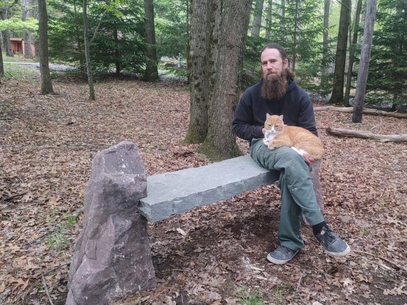 handsome man holding cat on stone bench