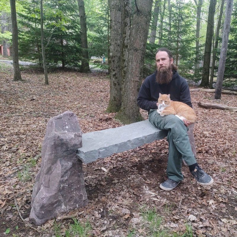 handsome man holding cat on stone bench